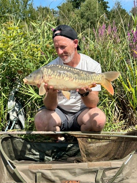 Guest holding a carp on the pontoon at Scotgate Cottage fishing lake